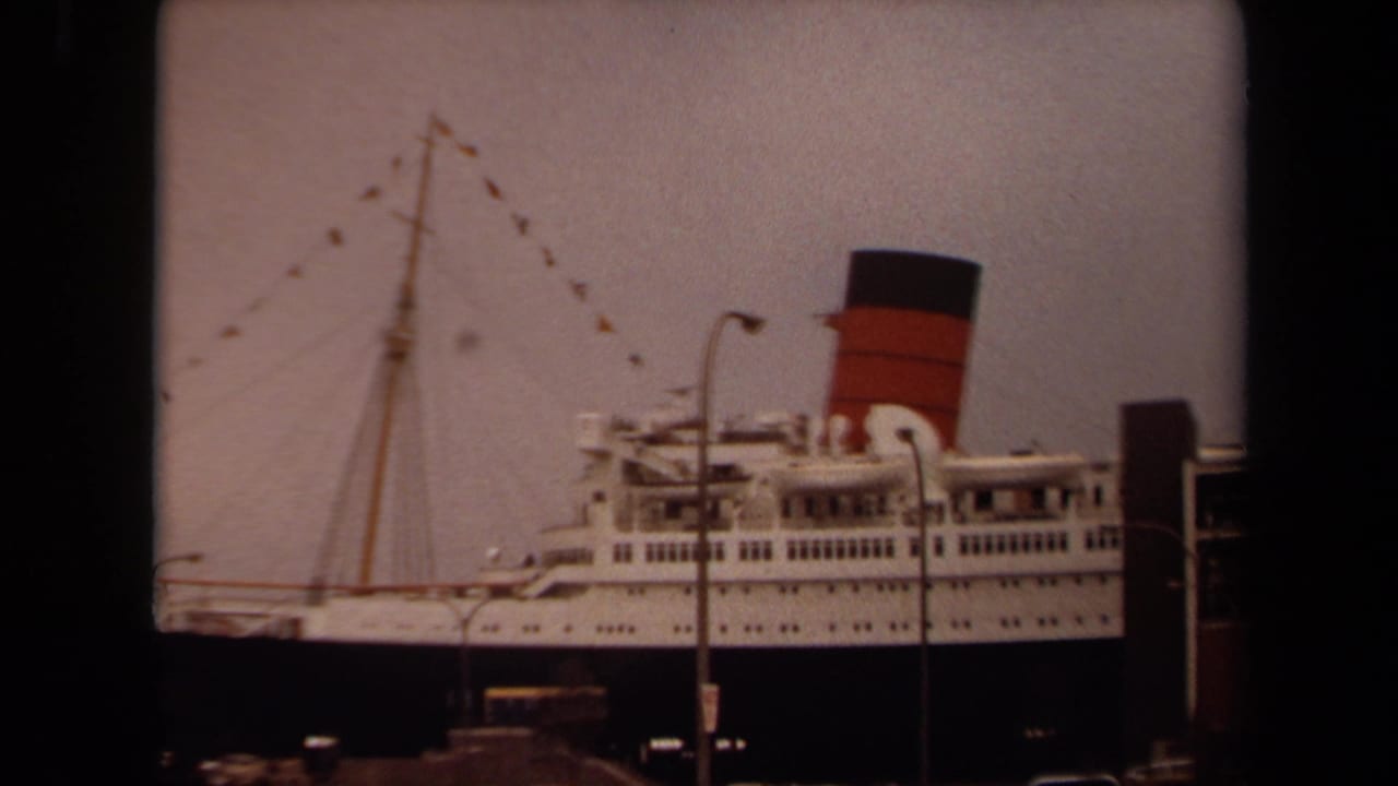 Ocean liner side with mast bunting, funnel, dock lights, and pier structure.
