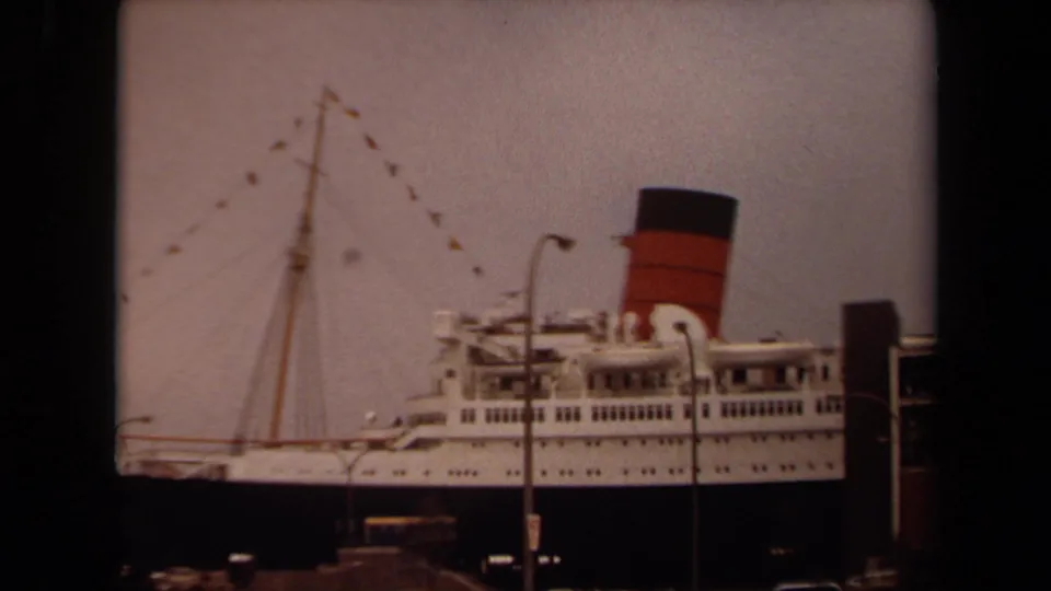 The Long Beach docked liner fills the frame, with bunting on the mast, a red-and-black funnel, deck rows, and dockside structures visible.