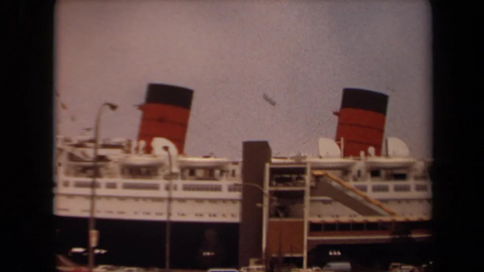 Final frame shows the docked liner at Long Beach with two red-and-black funnels, deck railings, gangway structure, dock lights, and a hazy sky.