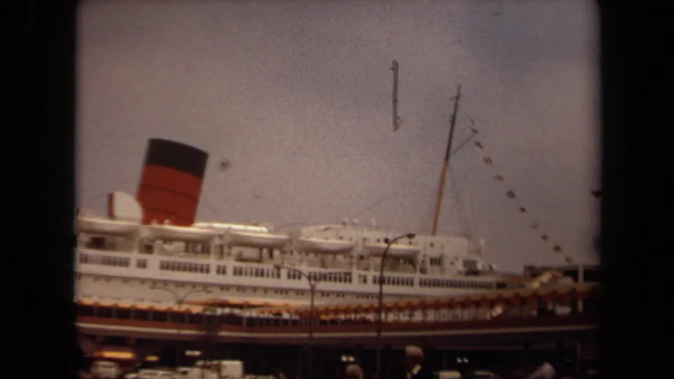 Side view of the Long Beach ocean liner in 1971, showing layered decks, rigging, pier structures, and warm faded 8mm color.