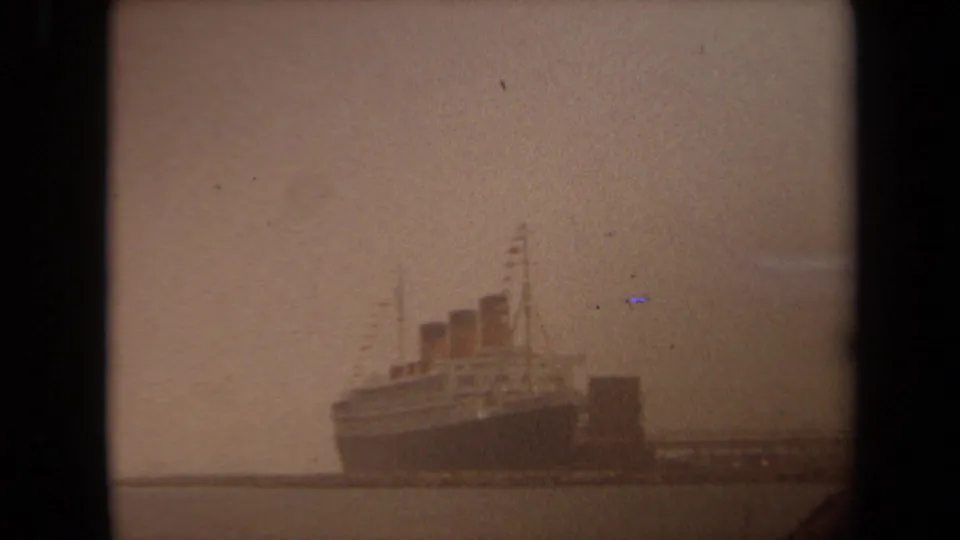 Soft, hazy Long Beach harbor frame from 1971 showing the docked liner with three funnels and a pier extending across the water.
