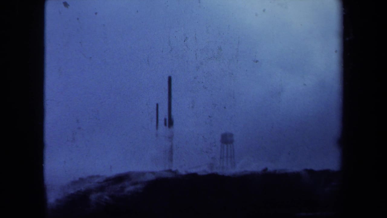 Soft distant towers and water tower on a ridge, framed by heavy film borders.