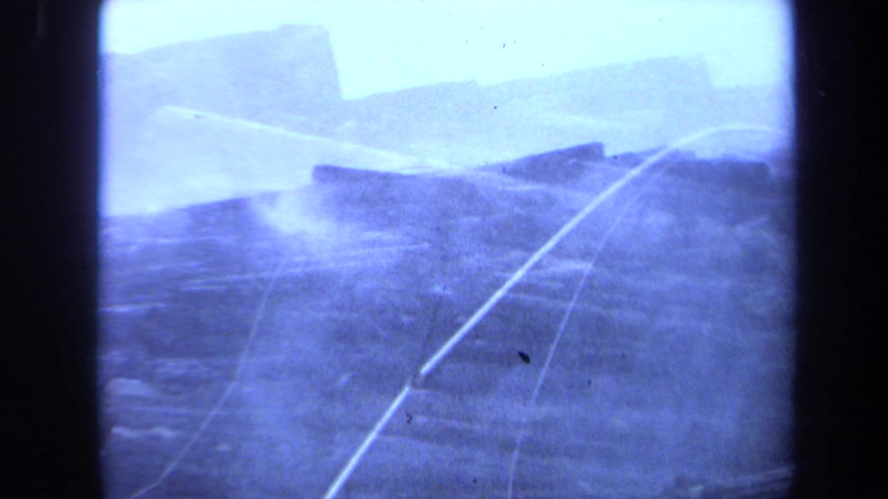 Hazy blue frame with long cut logs, smoke, and dark film edges.