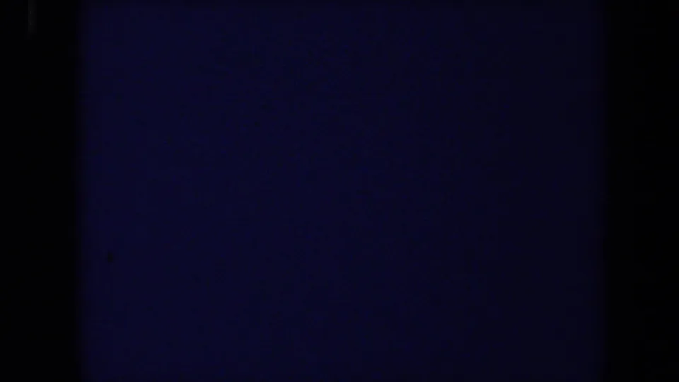 Dark transitional 8mm frame from the 1971 Maine clip, with only faint blue exposure along the edge.