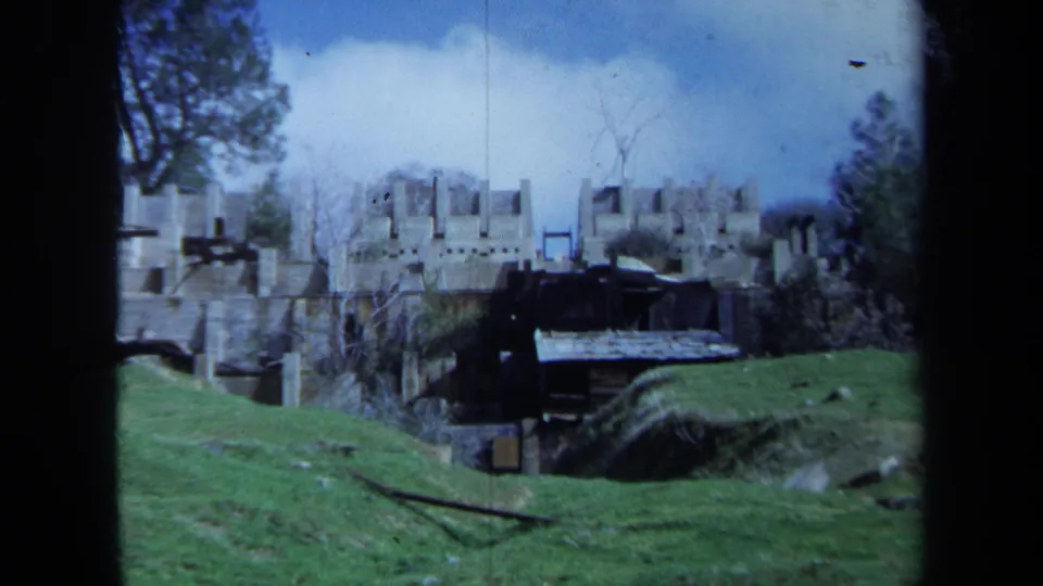 1971 Maine 8mm view of abandoned industrial structures and stone ruins set on a grassy hillside.