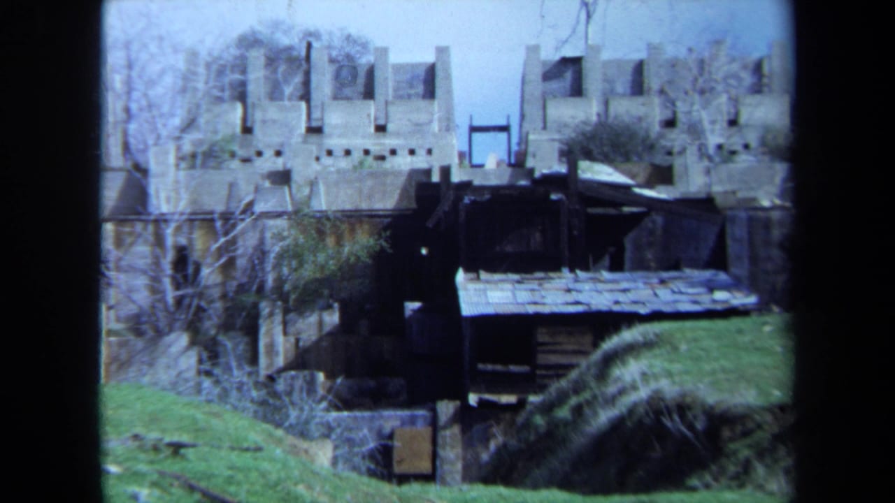 1971 Maine 8mm frame showing a waterside structure, grass, bare trees, and floodwater in a rural landscape.