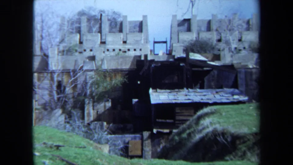 1971 Maine 8mm frame showing a waterside structure, grass, bare trees, and floodwater in a rural landscape.
