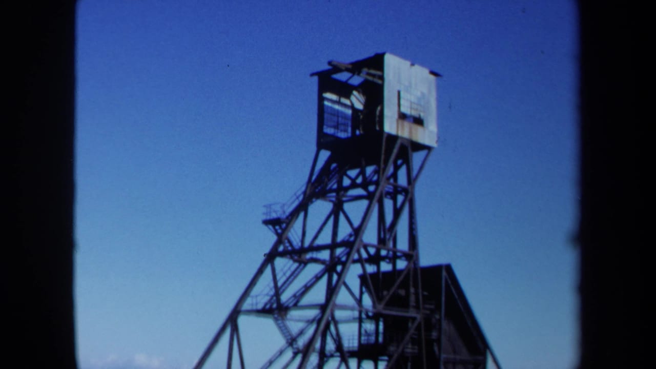 Upper section of a steel mine derrick against a clear blue sky.
