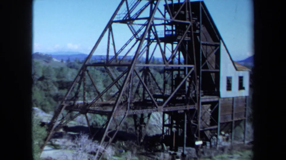 1971 Maine 8mm frame showing the full mine derrick structure with a small base building in a mountain landscape.