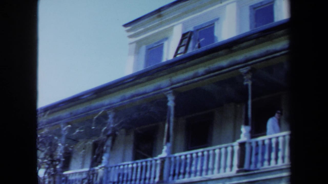 Large weathered house with porch columns, upper windows, and a ladder near the roofline.