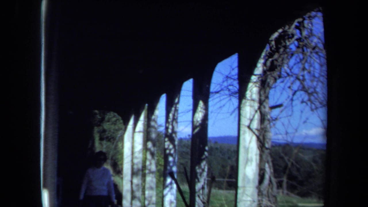 1971 Maine 8mm frame showing a person inside a dark abandoned structure with arched openings and blue sky outside.