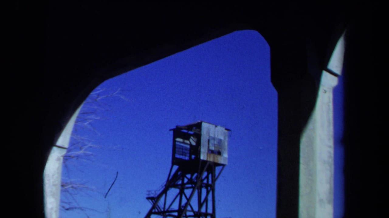 Mine headframe seen through a dark arched opening against a blue sky.