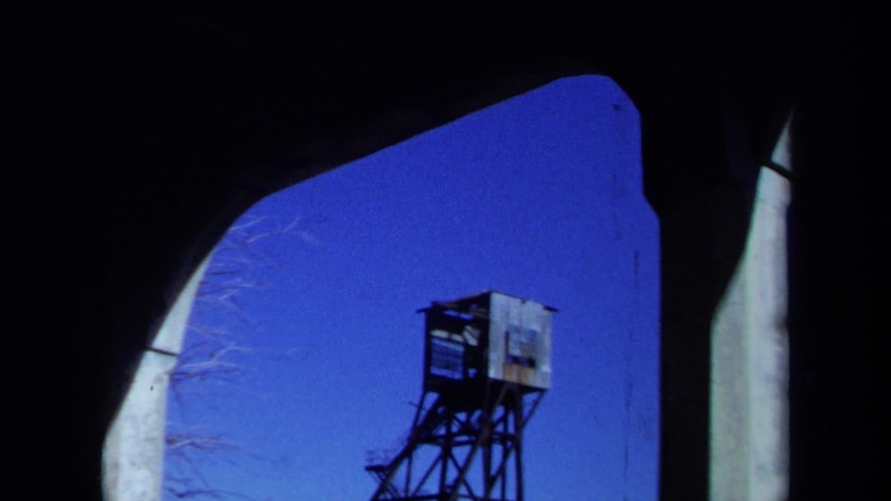 1971 Maine 8mm frame with the mine headframe lower in view, still bordered by a dark arched opening and pale vertical edge.