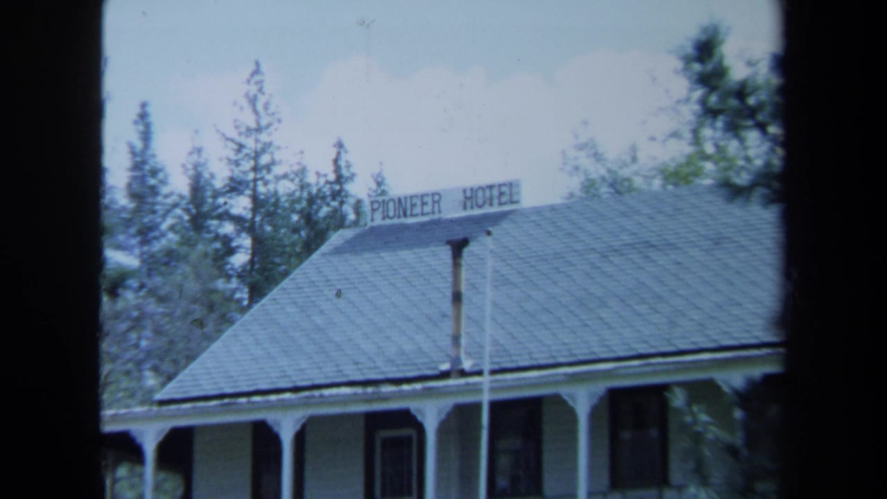 1971 Maine frame with the Pioneer Hotel sign on a gray roof above a white porch-fronted building in a wooded setting.