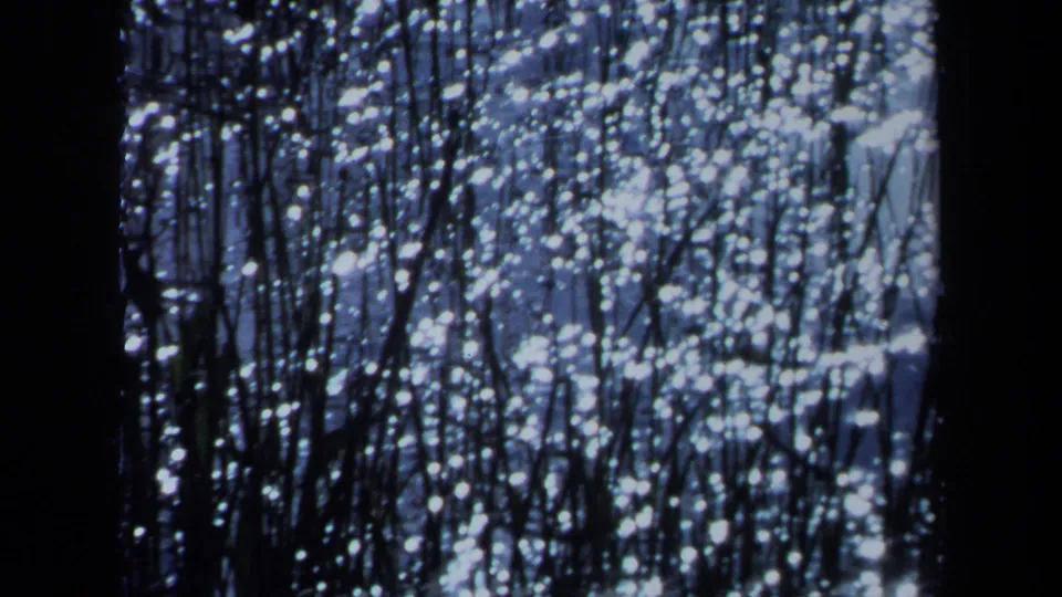 1971 Maine 8mm frame showing a blue, grainy field of bright speckles crossed by dark vertical lines and a central black band.
