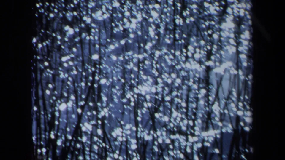 1971 Maine 8mm frame with shimmering white dots across a blue field, partly obscured by dark vertical bands.