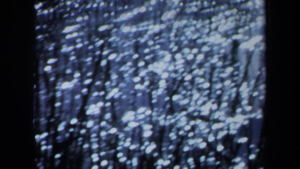 1971 Maine 8mm frame showing blurred white speckles on blue, interrupted by a broad dark vertical band.
