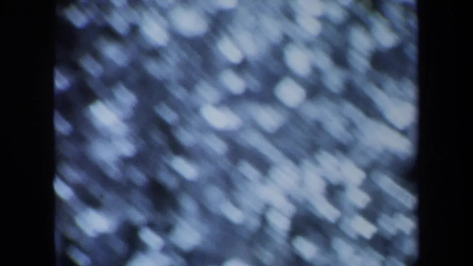 Zoomed 8mm close-up of water reflections in Maine, rendered as streaked blue-white bokeh and grain.