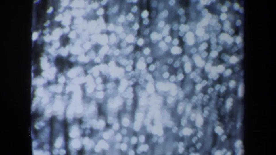 Final 8mm frame shifts into an unfocused abstract pattern of bright light spots and dark vertical shapes.