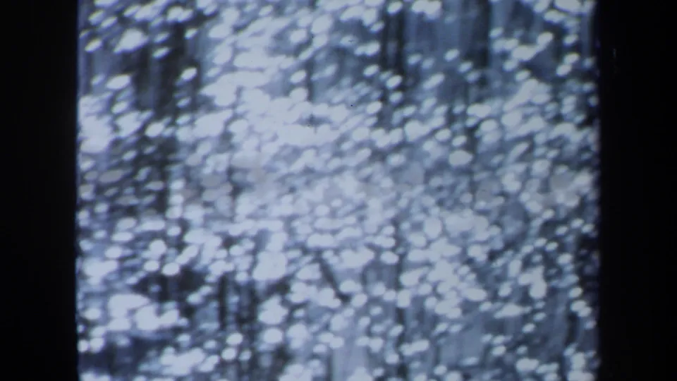 1971 Maine 8mm frame with dense soft white light spots, vertical streaks, and dark edges from the film or projection frame.
