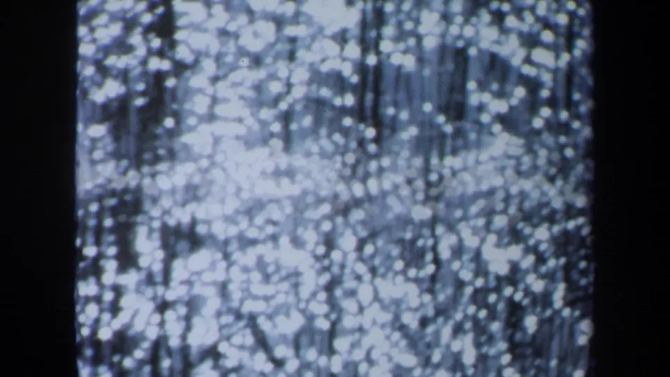 1971 Maine 8mm frame showing glowing soft-focus white lights, fine vertical lines, and dark side borders in a cool blue cast.