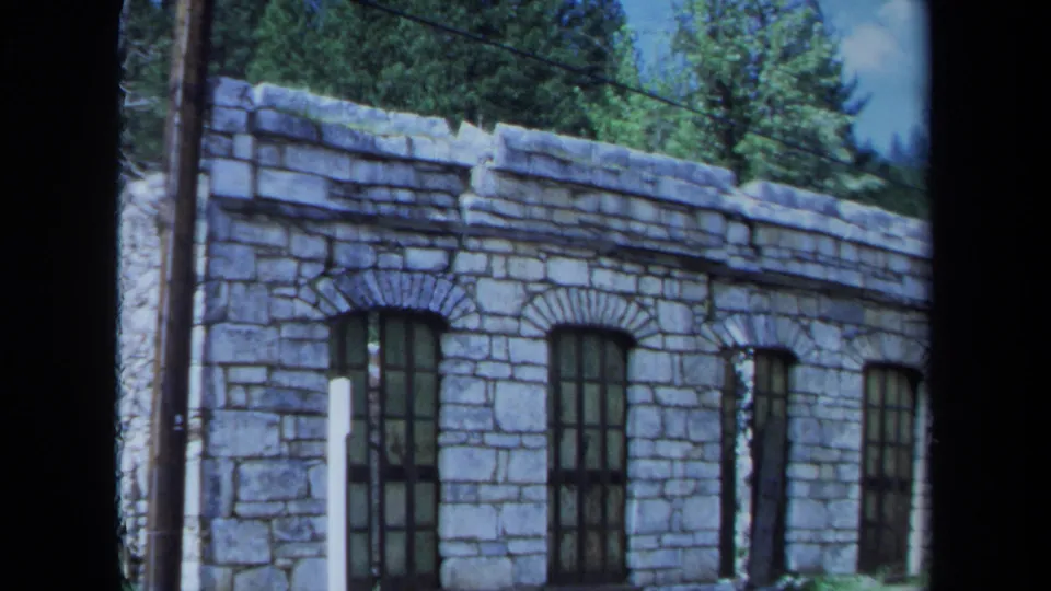 The camera frames the stone facade and tall arched windows of an unidentified Maine building in 1971 8mm footage.