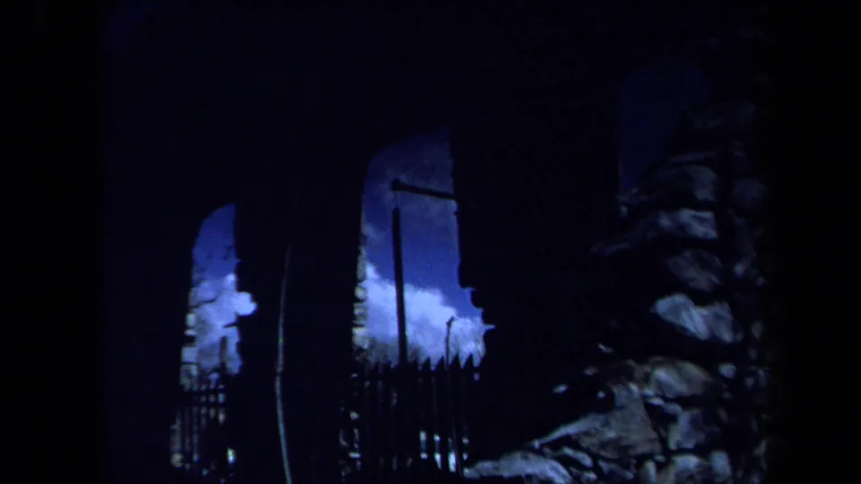 1971 Maine 8mm frame showing a dark lower view of arched stonework, vertical shadows, and bright sky through openings.