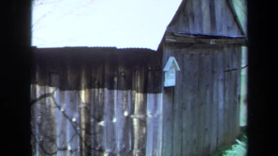 1971 Maine 8mm frame showing a wider view of the small weathered shack, with the Volcano's Jail sign mounted near the doorway.