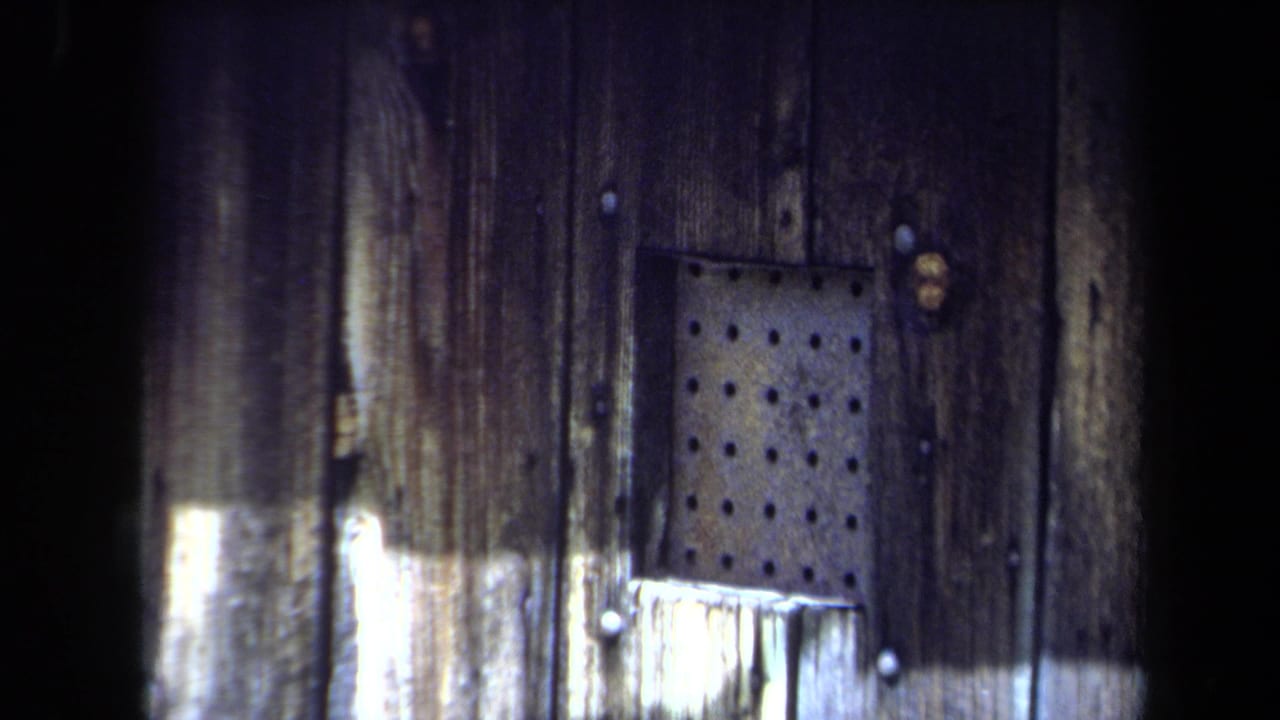 Second close view of weathered wooden siding and a perforated metal panel.