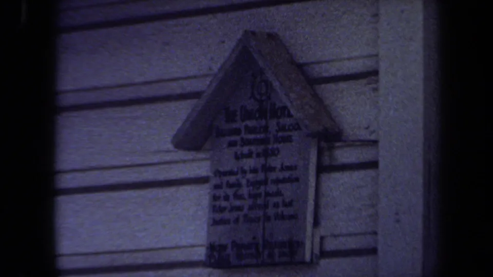 1971 Maine 8mm frame ending on a close view of the house-shaped Union Hotel marker in dim cool light.