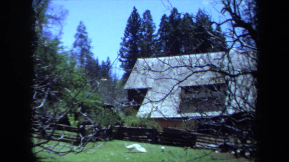 A rustic shingled house in Maine appears among evergreens, bare branches, lawn, and split-rail fencing in 1971 footage.