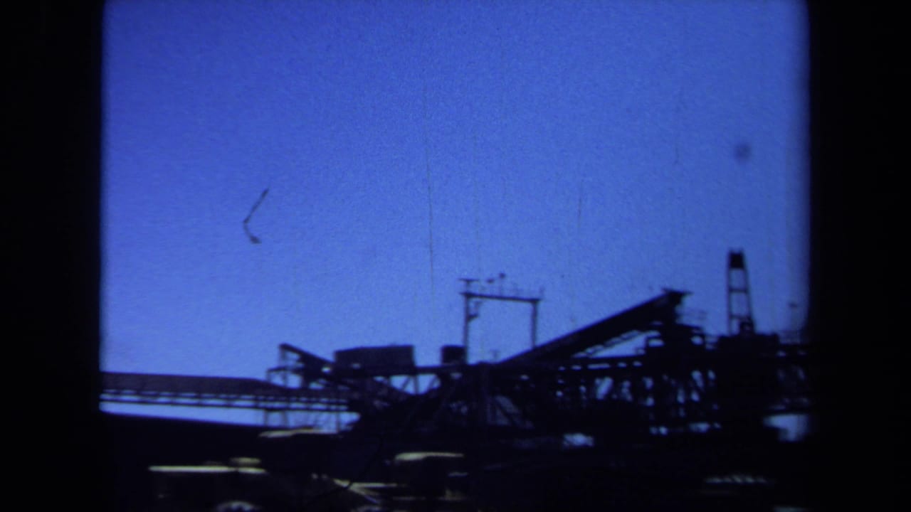 Industrial crane and conveyor-like structure silhouetted against blue sky.