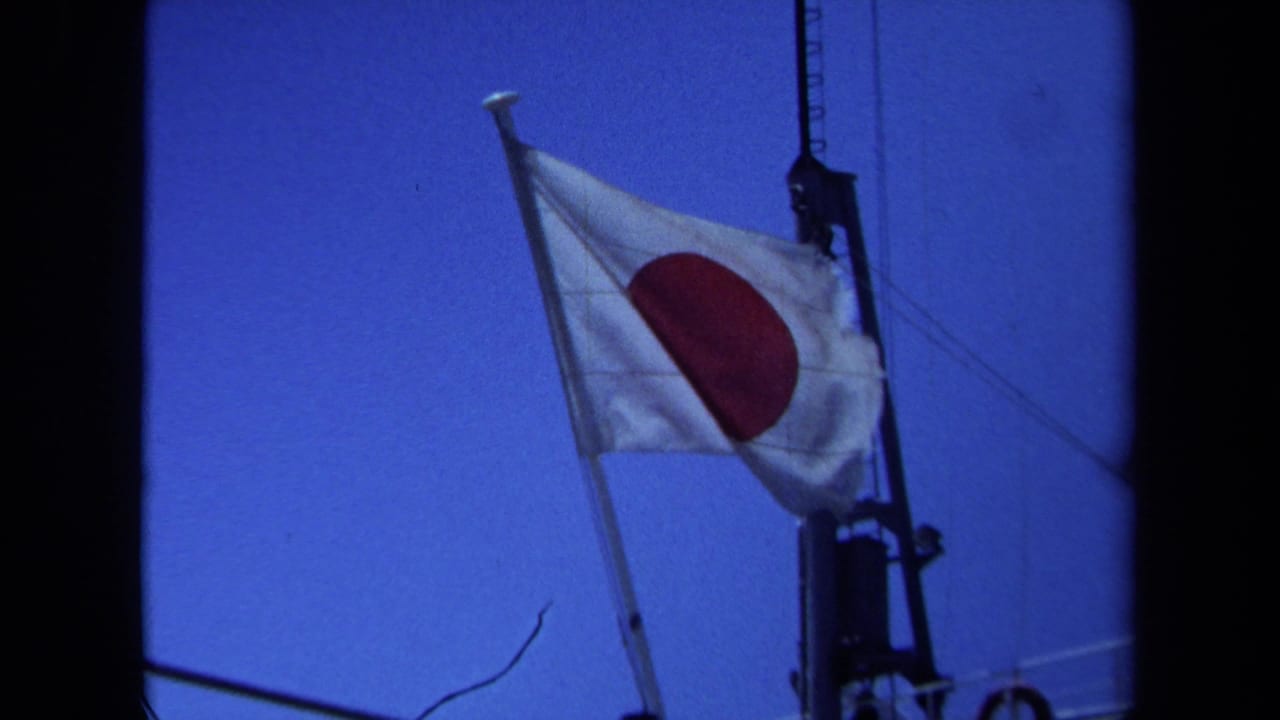 Japanese flag on a mast with rigging and blue sky in the background.