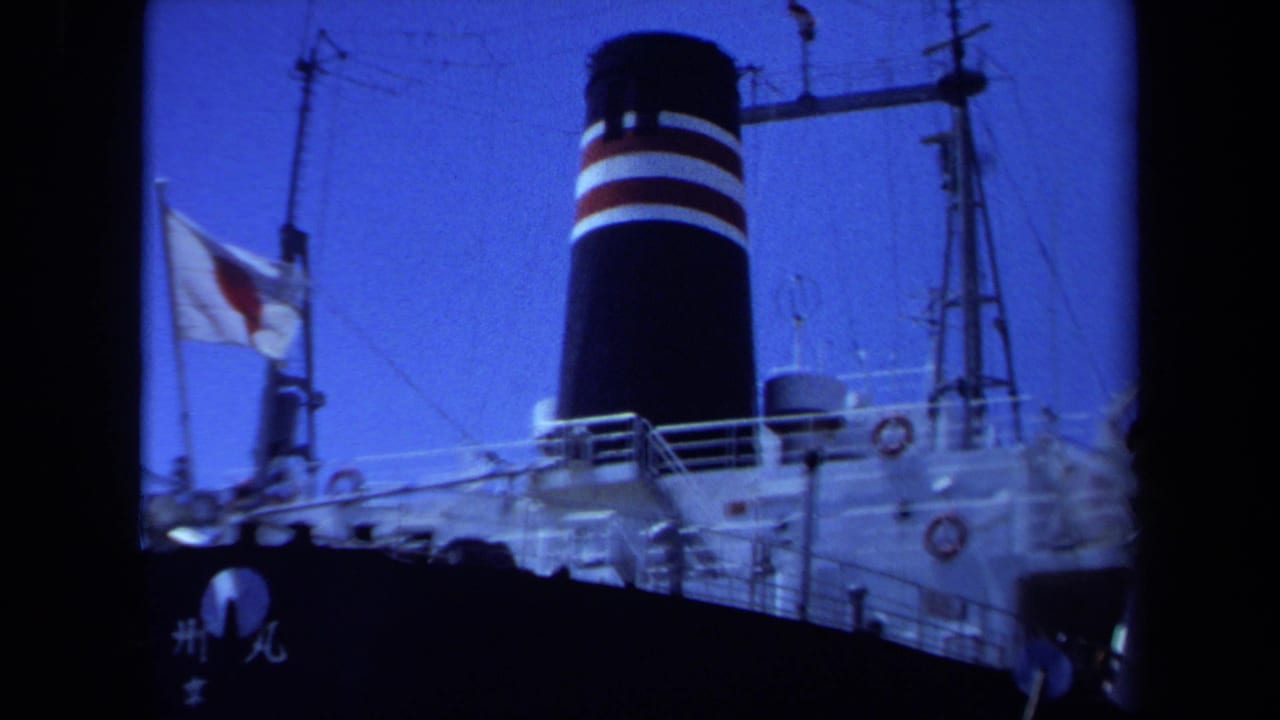 Cargo ship bow area with Japanese flag, funnel, railings, and rigging.