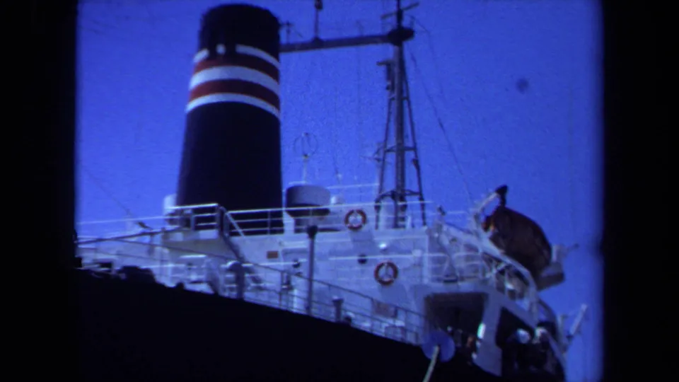 1971 Maine home-movie frame showing the Shin Honshu Maru deck with striped funnel, railings, lifebuoys, and rigging.