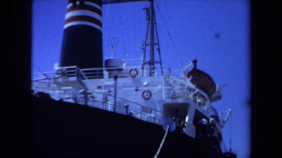 Final 8mm frame of the Maine cargo ship view, with funnel, rigging, deck railings, lifebuoys, and mooring equipment.