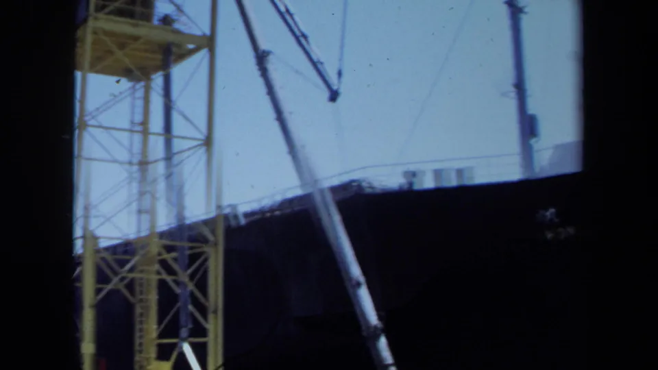 1971 Maine dockside view with a yellow gantry crane, ship rigging, and partial dark hull of the Honshu Maru.