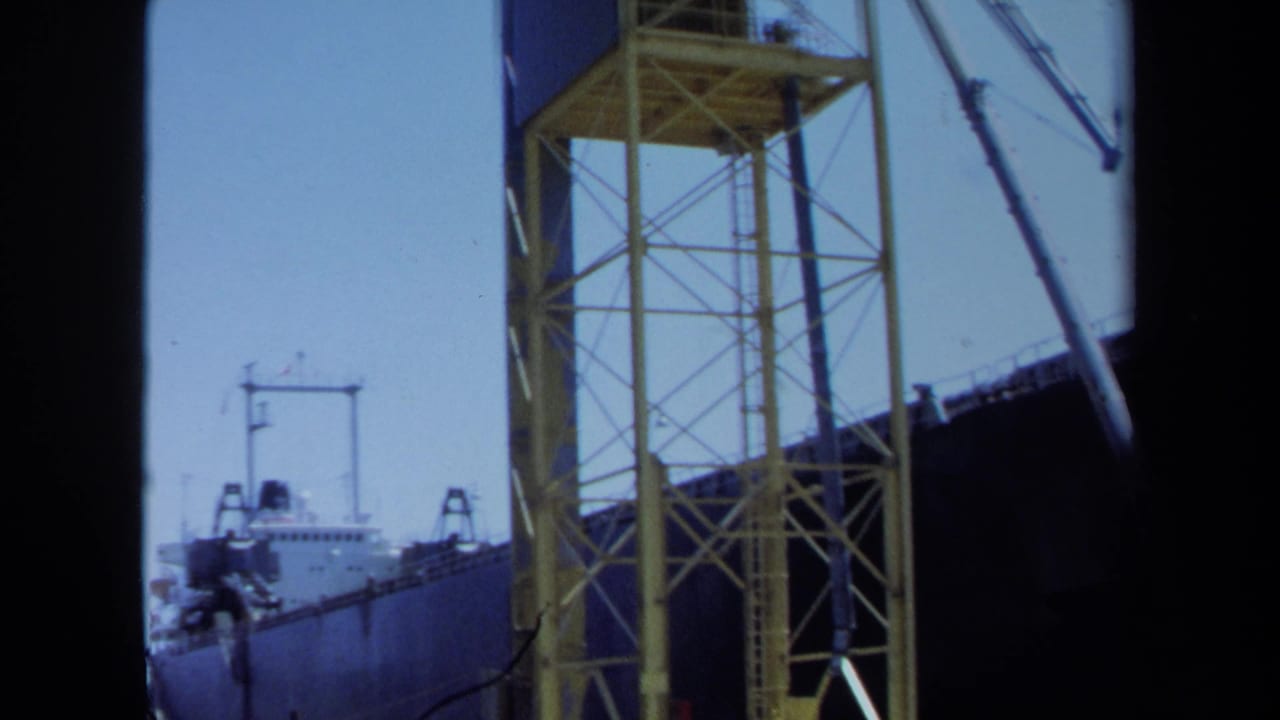 1971 Maine 8mm frame showing a docked cargo ship partly framed by a yellow truss structure and dark film borders.