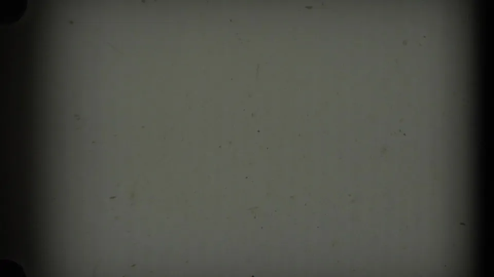 A mostly blank 8mm frame shows gray-green exposure, dust specks, and dark film-gate edges, with no clear subject visible.