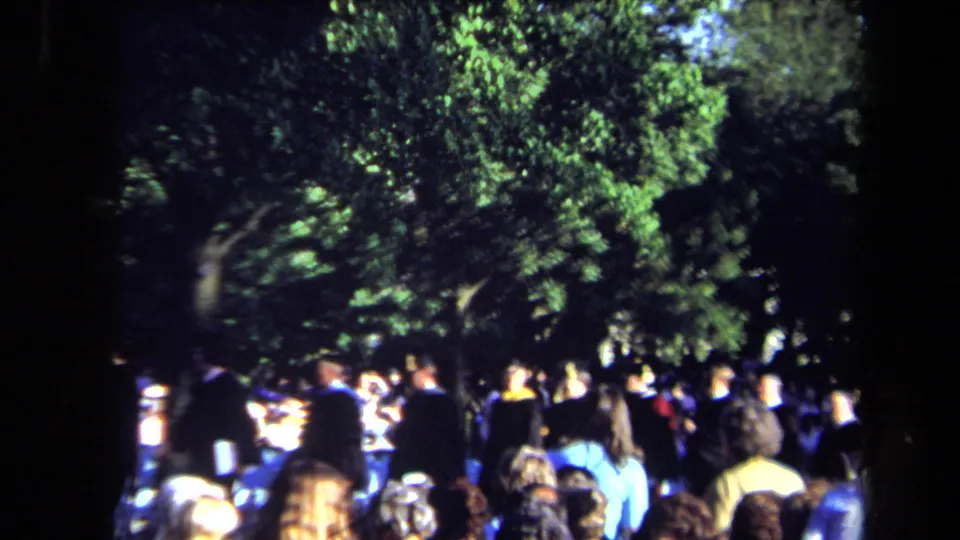 1971 outdoor graduation gathering in Sacramento with guests, graduates and dense green trees.
