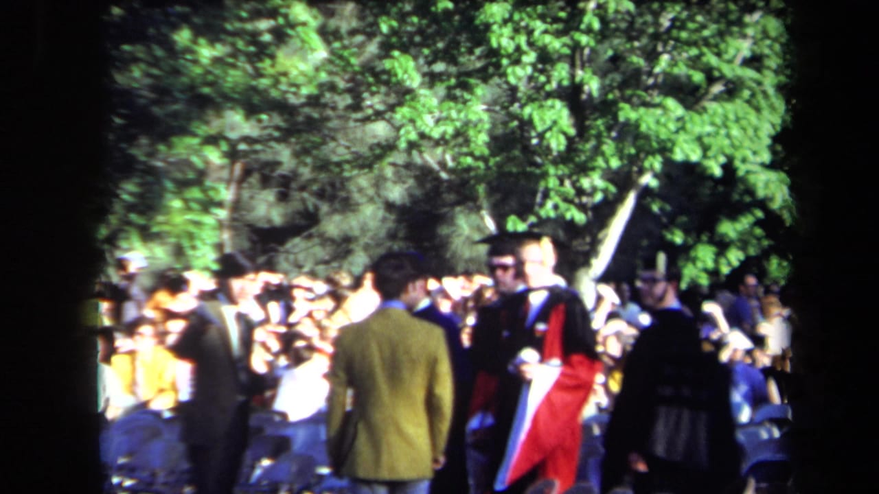 Outdoor 1971 Sacramento graduation crowd with caps, gowns, spectators, trees, and a red academic robe visible in sunlight.