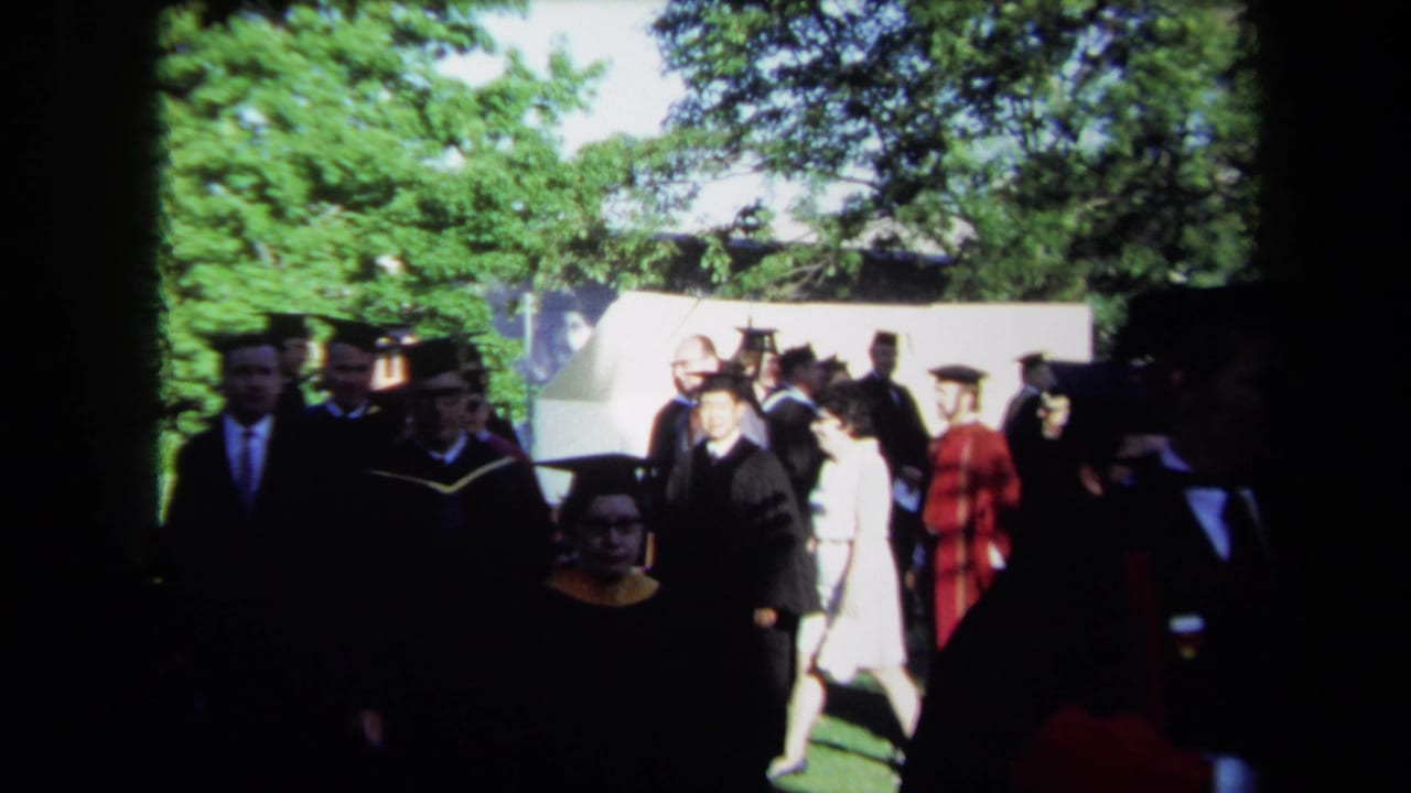 Graduates and faculty in black and red academic robes walk past spectators during the Sacramento convocation.
