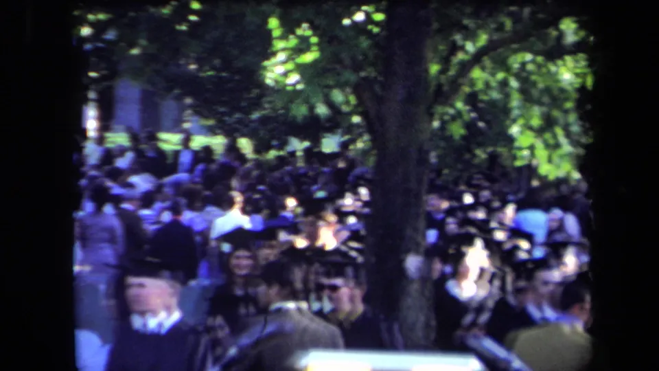 Sacramento 1971 home-movie view of graduates and attendees gathered outdoors beneath trees during a commencement ceremony.