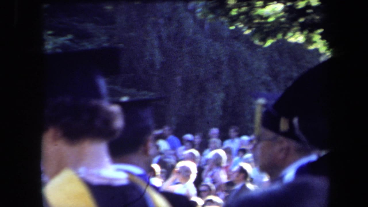 1971 Sacramento graduation frame with a capped graduate in profile and spectators seated in the background under trees.