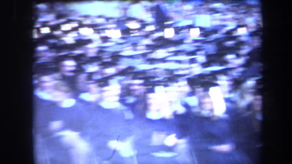 Blurred Sacramento concert frame showing blue stage light, bright flares, and a probable microphone stand amid heavy motion blur.