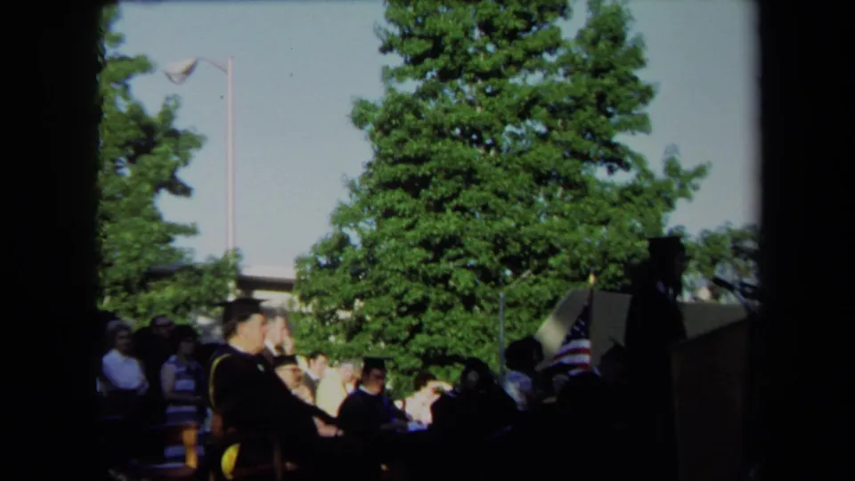 Seated graduate and audience members are visible at an outdoor 1971 Sacramento graduation ceremony.