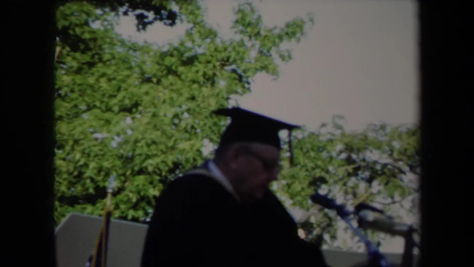 The graduation speaker appears to look down toward notes at a Sacramento outdoor commencement in 1971.