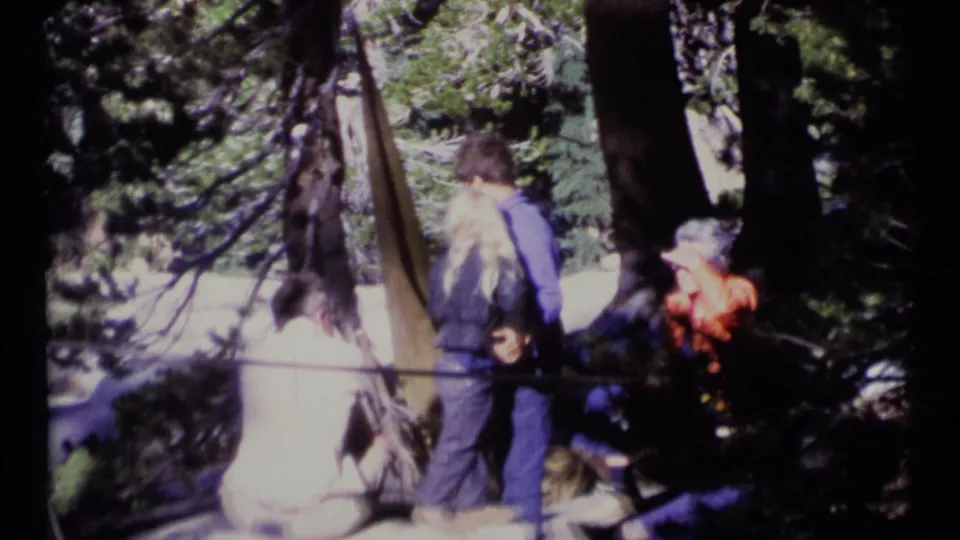In the Montana forest setting, the couple remains close together near a tree with another adult seated nearby.