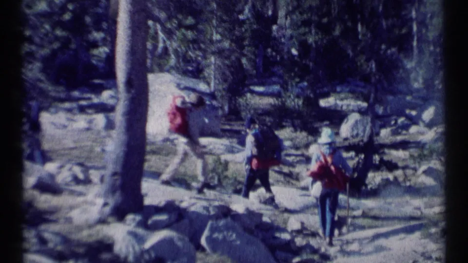 Backpackers cross a rocky forested area in Scapegoat Wilderness, Montana, as captured on 1973 8mm film.