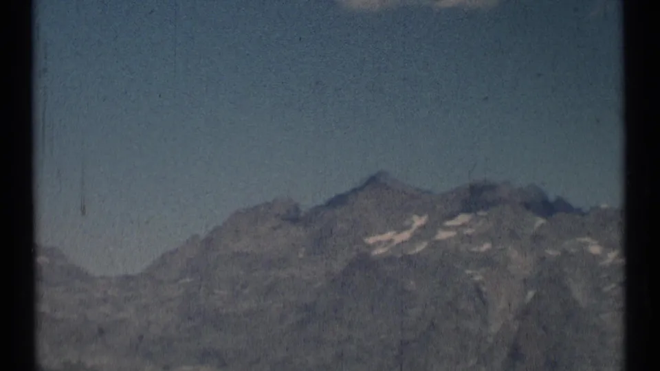 1973 8mm home-movie frame of distant mountain ridges in Scapegoat Wilderness, Montana, with muted color and visible film borders.